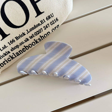 Sweet Striped Acrylic Hair Claw in pastel blue and cream stripes on a wooden surface.