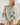 Model wearing a Striped Yoke Top with a relaxed fit in a light green color, paired with beige shorts.