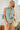 Model wearing a Striped Yoke Top with a relaxed fit in a light green color, paired with beige shorts.