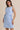 Light blue boat neck sleeveless side tie mini dress worn by a model, front view.