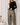 Model wearing black Boat Neck Semi Bell Long Sleeve Knit Top with beige patterned pants