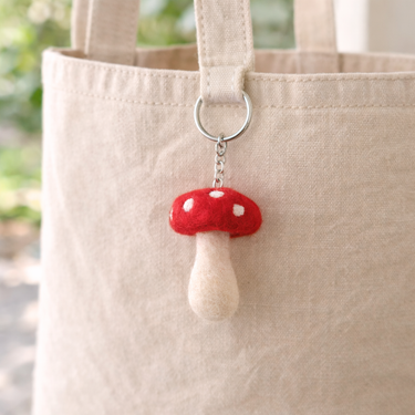 Felt Mushroom Keychain Bag Charm attached to a beige tote bag, showcasing its vibrant and eco-friendly design.