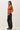 Side view of model wearing orange button-up cardigan with black pants