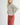 Front three-quarter view of model wearing Irisha oatmeal diamond pointelle sweater with red pants