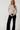 Full-length view of model wearing white Boat Neck Semi Bell Long Sleeve Knit Top with black pants