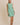 Model wearing a BOAT NECK SLEEVELESS SIDE TIES MINI DRESS with vertical stripes in green and white.