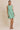 Model wearing a BOAT NECK SLEEVELESS SIDE TIES MINI DRESS with vertical stripes in green and white.