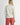Back view of model wearing Irisha oatmeal diamond pointelle sweater with red pants
