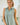 Model wearing a Striped Yoke Top in green with sleeveless design and button details, showcasing casual summer style.