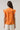 Back view of Donna Dot Hessi Button Down Top with ruffled cap sleeves and floral print on a vibrant orange background.