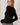 Side view of model wearing black Boat Neck Semi Bell Long Sleeve Knit Top with patterned pants