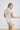 White collared V neck button down line lace detail shirt with beige shorts, front view