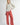 Front three-quarter view of model wearing Irisha oatmeal diamond pointelle sweater with red pants
