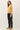 Side view of model wearing yellow button-up cardigan with black pants