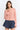 Pearl Button Ribbed Knit Cardigan in pink styled on a model with denim shorts