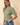 Side view of model wearing sage green ribbed knit top with blue jeans