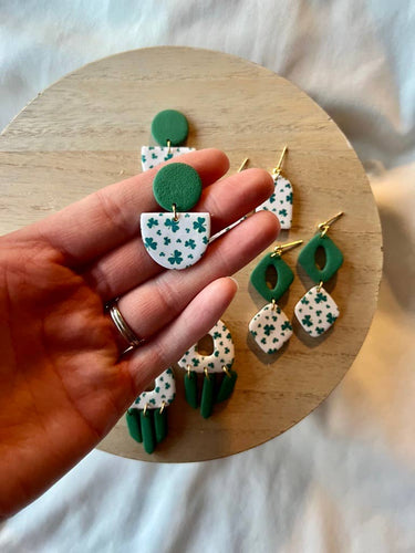 St. Patrick's Day Earrings Clover Clay Earrings Lucky displayed in a hand, featuring green and white designs.