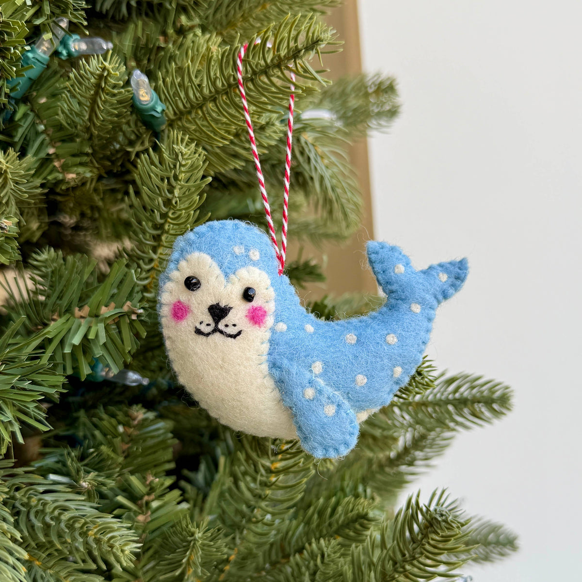 Leopard Seal Felt Wool Christmas Ornament displayed on greenery