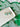 Shamrock Heart Earrings Clover Heart Earrings on a white plate against a green patterned background.