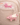 Pink felt flying pig keychain displayed on a beige pouch