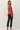 Back view of model wearing red raglan sleeve pullover sweater with black pants