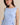 Close-up of a model wearing a light blue boat neck sleeveless side tie mini dress.