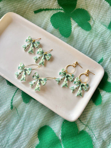 Clover Bow Earrings Shamrock Bow Earrings Lucky Bow displayed on a plate with shamrock background.