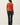 Back view of model wearing orange button-up cardigan with black pants