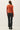 Back view of model wearing orange button-up cardigan with black pants