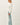 Side view of model wearing light-colored raglan sleeve pullover sweater with jeans