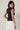 HIGH NECK EXTENDED SHOULDER SIDE RUCHED POLKA DOT TOP worn by a model from the back, showcasing the stylish design and polka dot pattern.