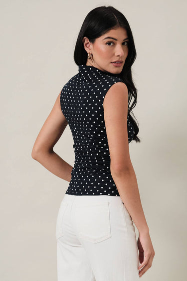 HIGH NECK EXTENDED SHOULDER SIDE RUCHED POLKA DOT TOP worn by a model from the back, showcasing the stylish design and polka dot pattern.