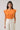 Model wearing Donna Dot Hessi Button Down Top with floral print and ruffled cap sleeves in vibrant orange.