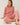 Model wearing pink cotton modal fleece sweatshirt, seated pose