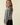 Side view of model wearing gray striped round neck long sleeve sweater with black pants