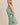 Model wearing BOAT NECK SLEEVELESS SIDE TIES MINI DRESS in green and white stripes.