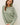 Model wearing sage green raglan sleeve slub pullover sweater, front view