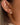 Close-up of Lush 18K Gold Non-Tarnish CZ Pave Huggie Earrings worn on ear, showcasing cubic zirconia detail.