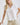 Close-up of white collared V neck button down line lace detail shirt with beige shorts