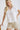 Close-up of white collared V neck button down line lace detail shirt with beige shorts