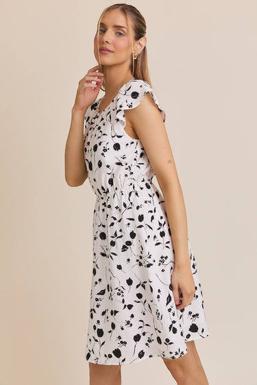 ROUND NECK RUFFLE SHORT SLEEVE FLORAL PRINT DRESS worn by a model with floral patterns.
