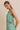Model wearing BOAT NECK SLEEVELESS SIDE TIES MINI DRESS in green and white stripes,side view