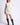 Full-length view of model wearing Chiara white long-sleeve pullover sweater with black knee-high boots
