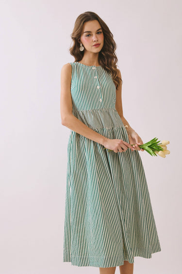 Model wearing Striped Smocked Waist Round Neck Midi Dress holding tulips, showcasing its striped pattern and relaxed fit.