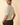 Back view of model wearing cream ribbed knit top with brown pants