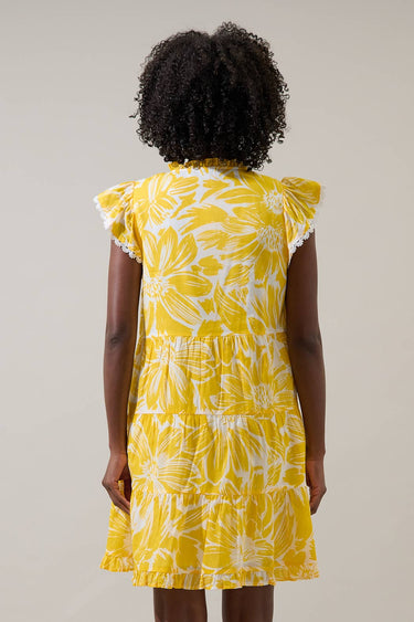 Back view of a model wearing the Joni Floral Yodi Shift Mini Dress in yellow floral print with ruffle sleeves.