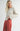 Side view of model wearing Irisha Diamond Pointelle Sweater in Oatmeal, with red pants