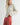 Side view of model wearing Irisha Diamond Pointelle Sweater in Oatmeal, with red pants
