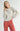 Model wearing Irisha oatmeal diamond pointelle sweater with red pants, hand on hip
