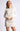 Model wearing Chiara white long-sleeve pullover sweater with white shorts